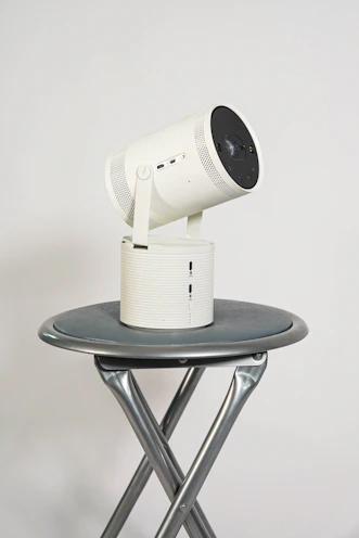 A projector setup on a wooden table with eucalyptus leaves nearby, highlighting its Australian registration.