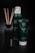 A set of personal care products, including a bottle with reeds, a foaming shower gel, and a soothing body cream tube from the Ritual of Jing collection. The containers are predominantly dark green with minimalist labels, set against a black background that highlights their luxurious appearance.