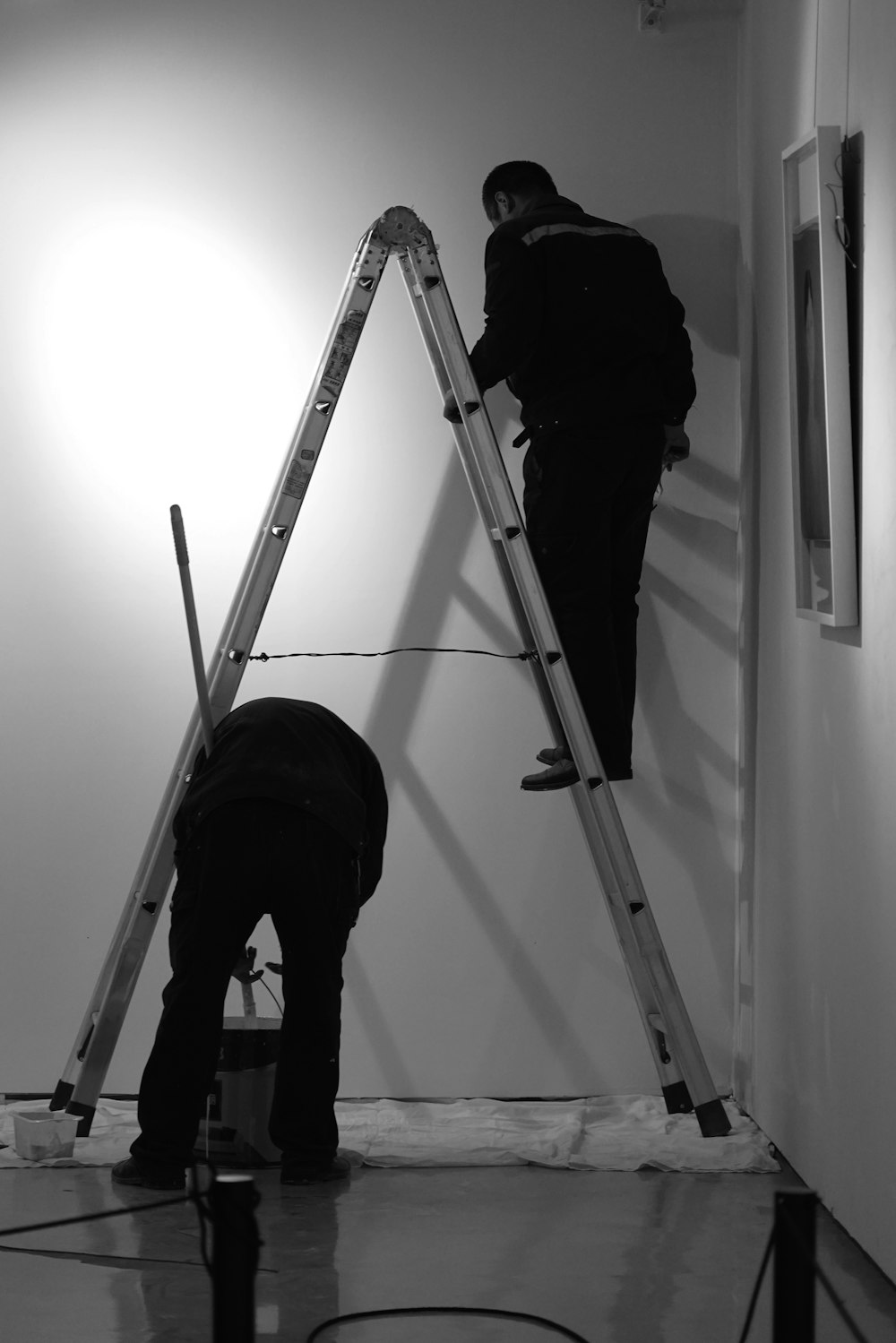 두 남자가 사다리로 벽을 칠하고 있다