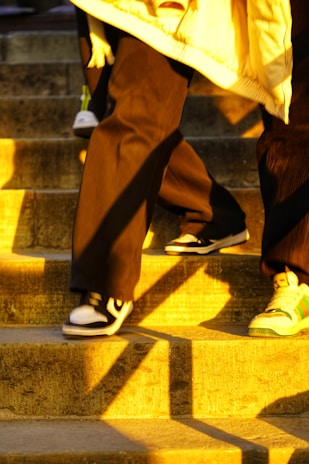 A happy customer walking confidently down a sunlit street wearing mithrasshoes sneakers.