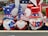 A display of decorative gnome figurines wearing patriotic attire, each featuring a long white beard and oversized hats in red, white, and blue adorned with stars. They hold various signs, such as 'I Love USA', 'Welcome', and other American-themed imagery. The collection appears to be for sale, as indicated by a price tag visible below.