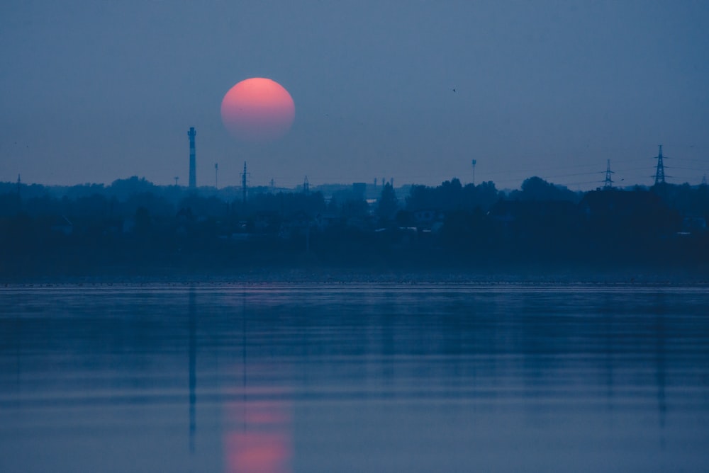 a large body of water with a sunset in the background