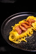 a plate of pasta with bacon on it