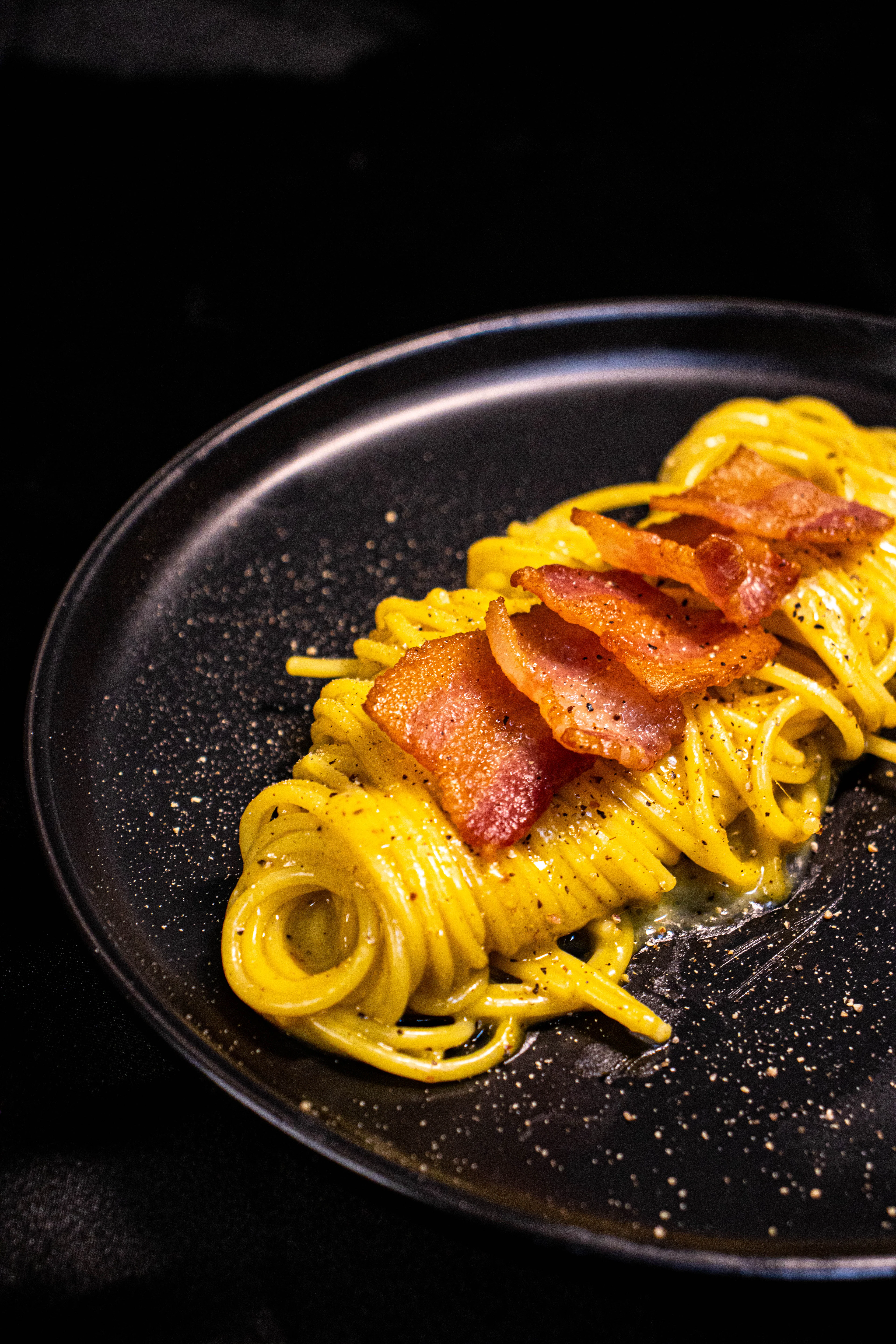 A nest of spaghetti in golden egg-and-cheese sauce topped with crisp cured pork and cracked black pepper, Rome's signature carbonara