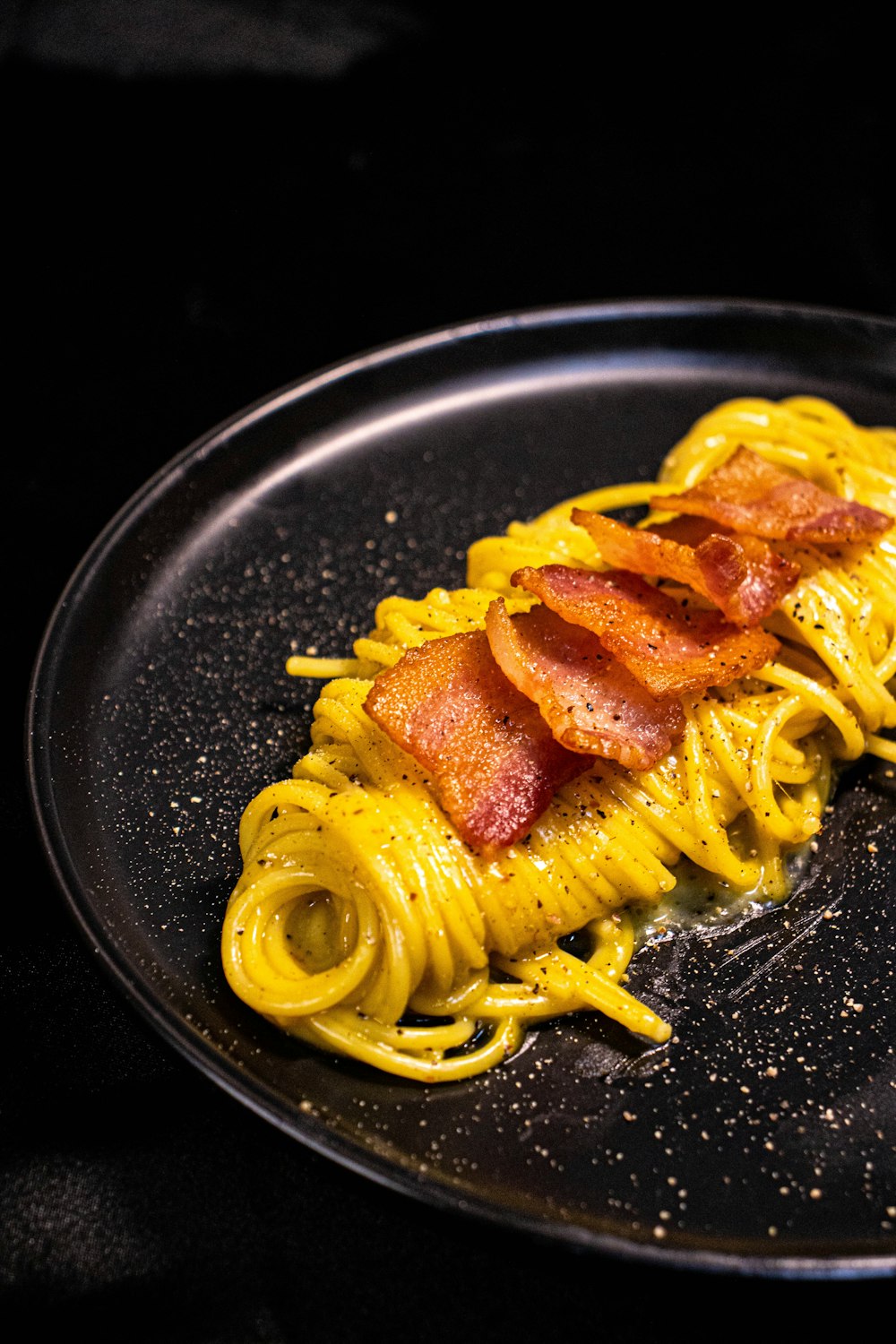 a plate of pasta with bacon on it