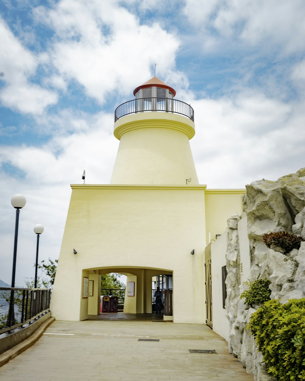 a white lighthouse with a red top on a cloudy day