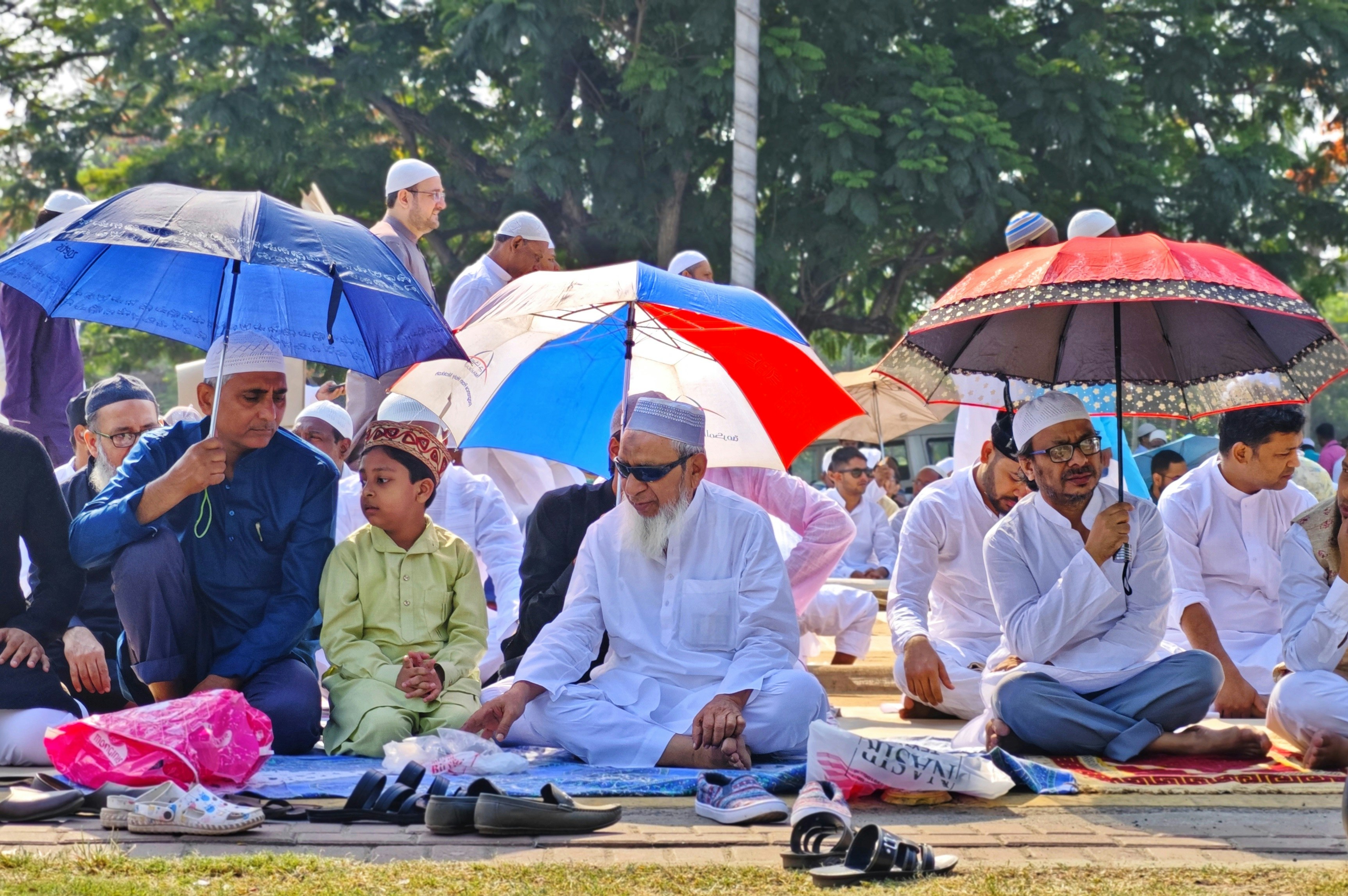 a group of people sitting on the ground under umbrellas