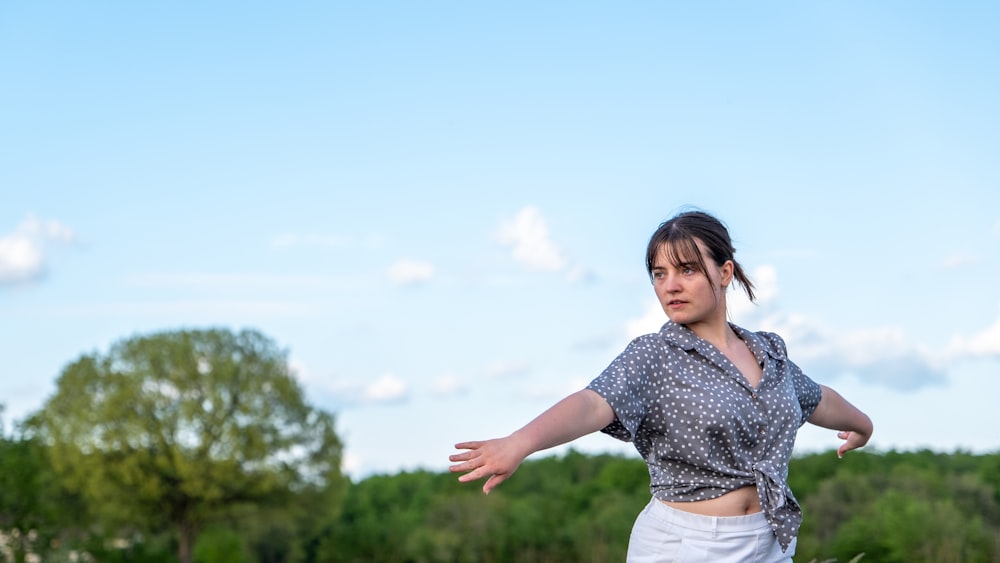 a woman is throwing a frisbee in a field