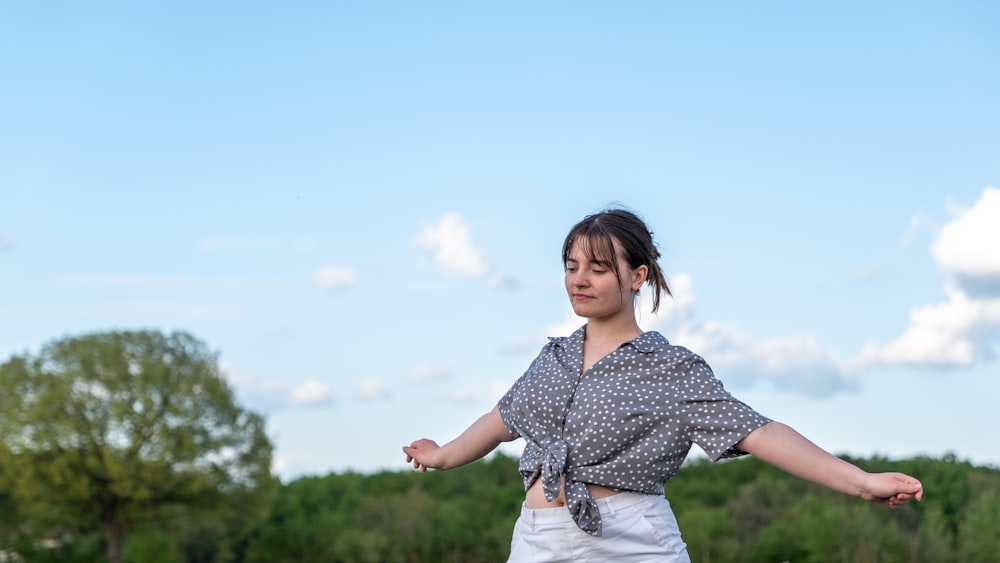 a woman standing in a field with her arms outstretched