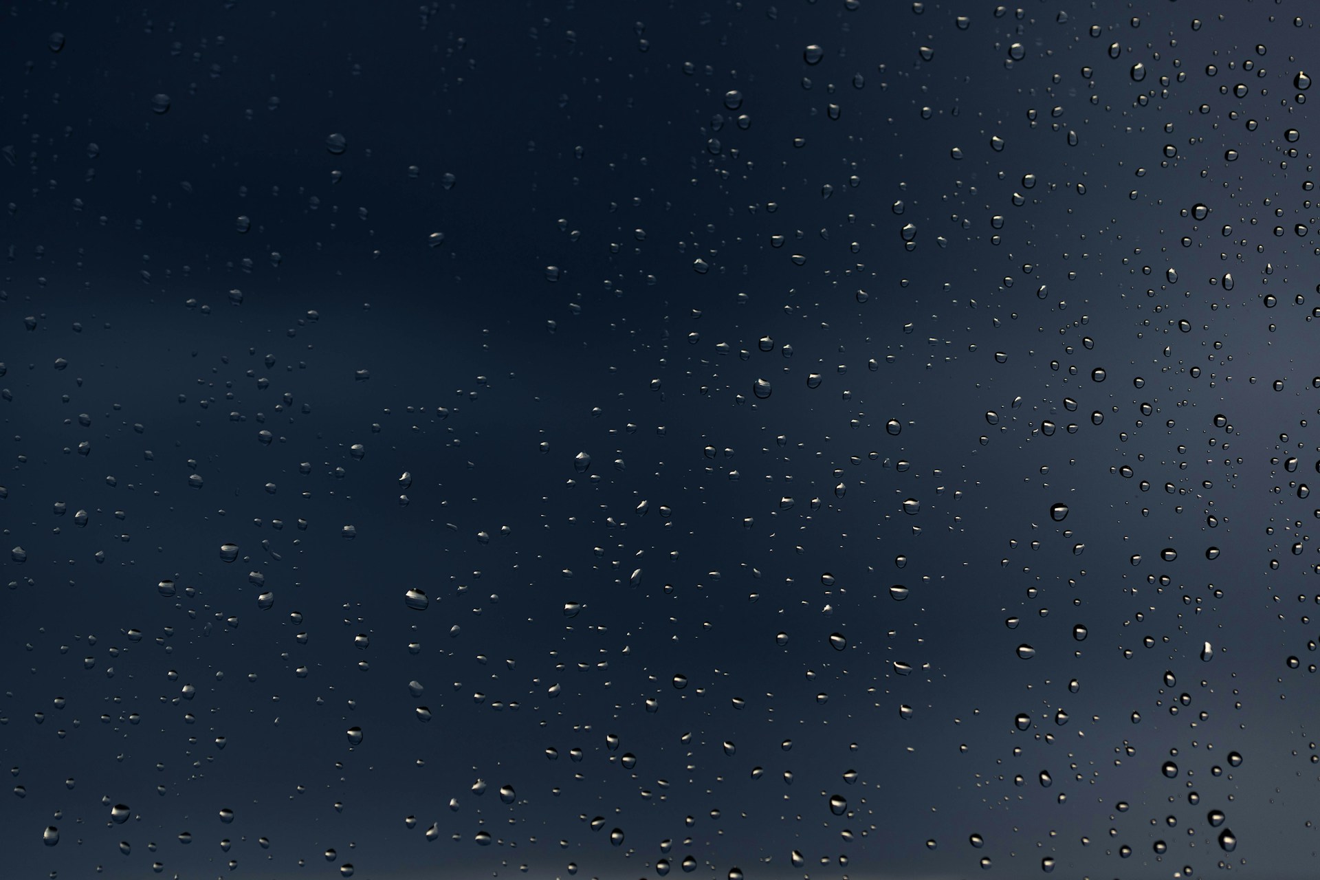 rain drops on a window with a dark blue sky in the background