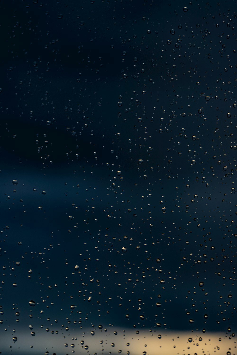 rain drops on a window with a dark sky in the background