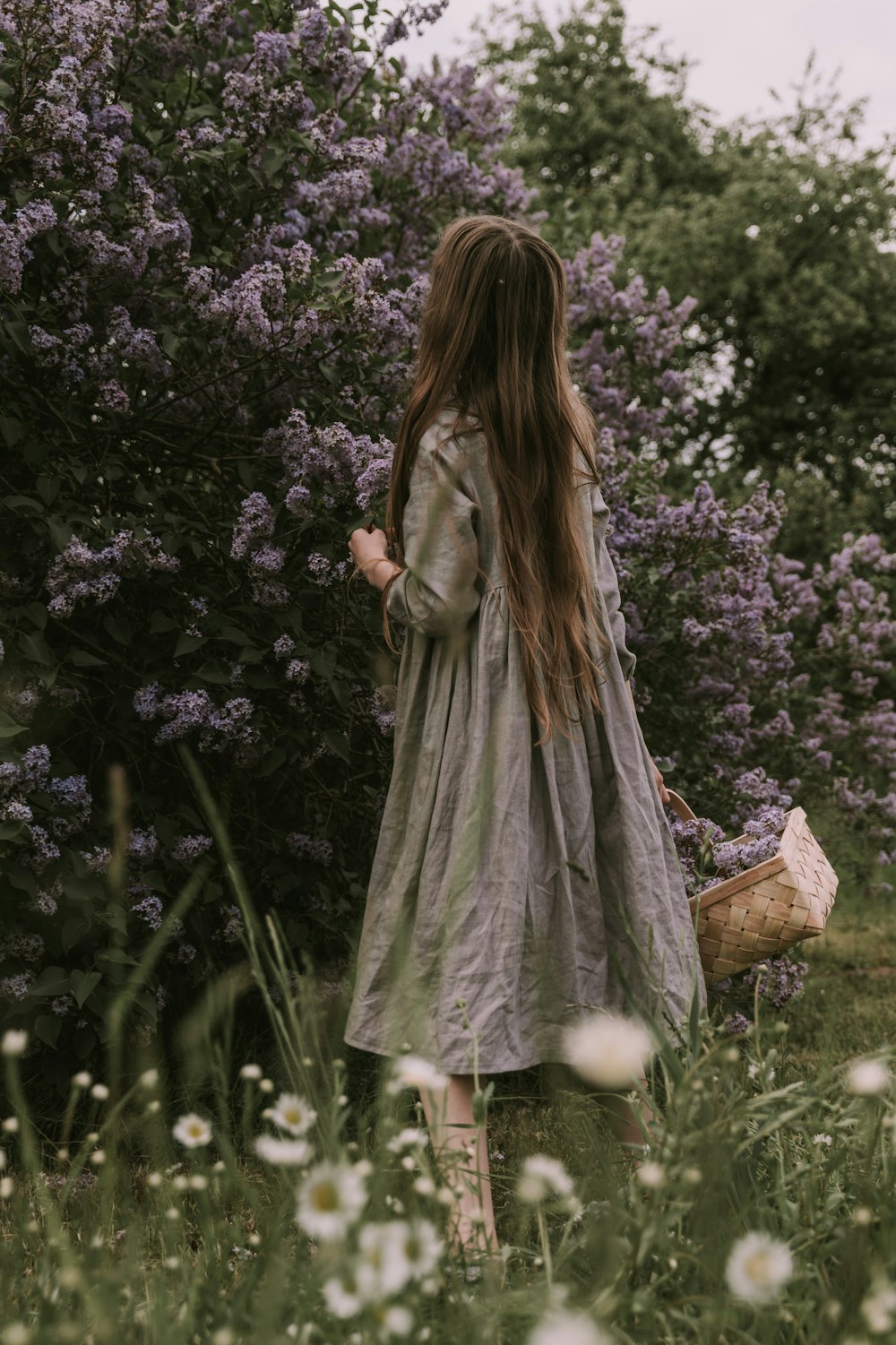 a girl in a dress walking through a field of flowers