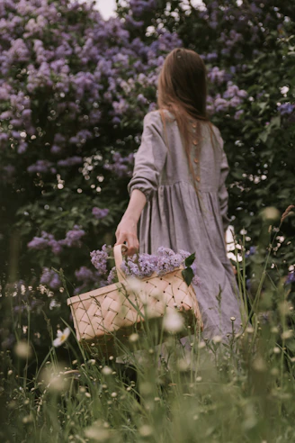 a woman holding a basket in a field of flowers