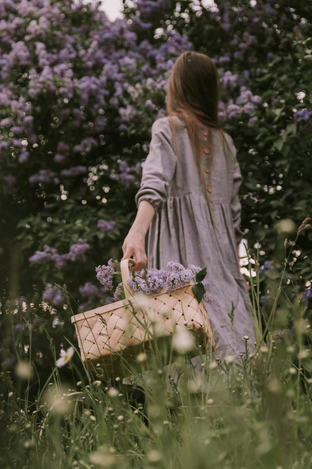 a woman holding a basket in a field of flowers
