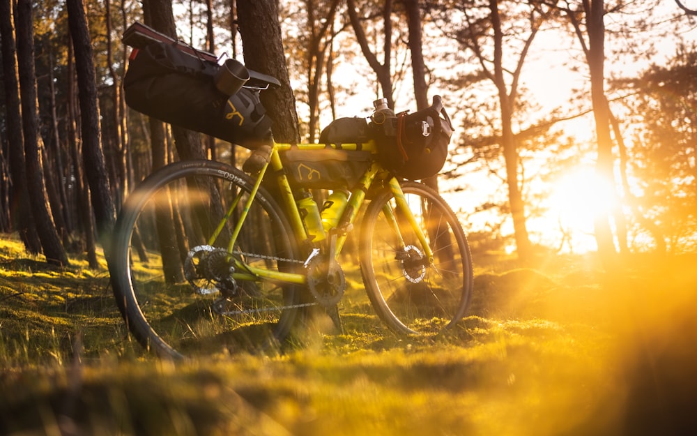 a yellow bike parked in a forest with the sun shining through the trees
