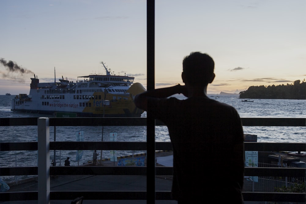 a man is looking out at a boat in the water