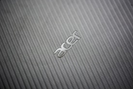 A close-up view of a textured, woven pattern surface with the metallic logo of a technology brand prominently displayed.