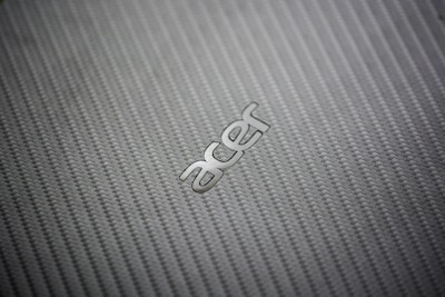 A close-up view of a textured, woven pattern surface with the metallic logo of a technology brand prominently displayed.