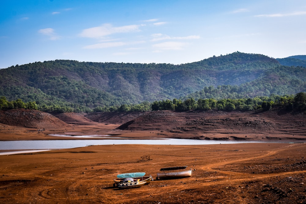 a couple of boats sitting on top of a dirt field