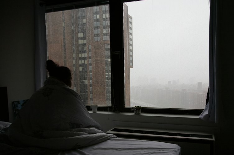 A person sitting quietly with a phone in hand, looking contemplative in soft evening light