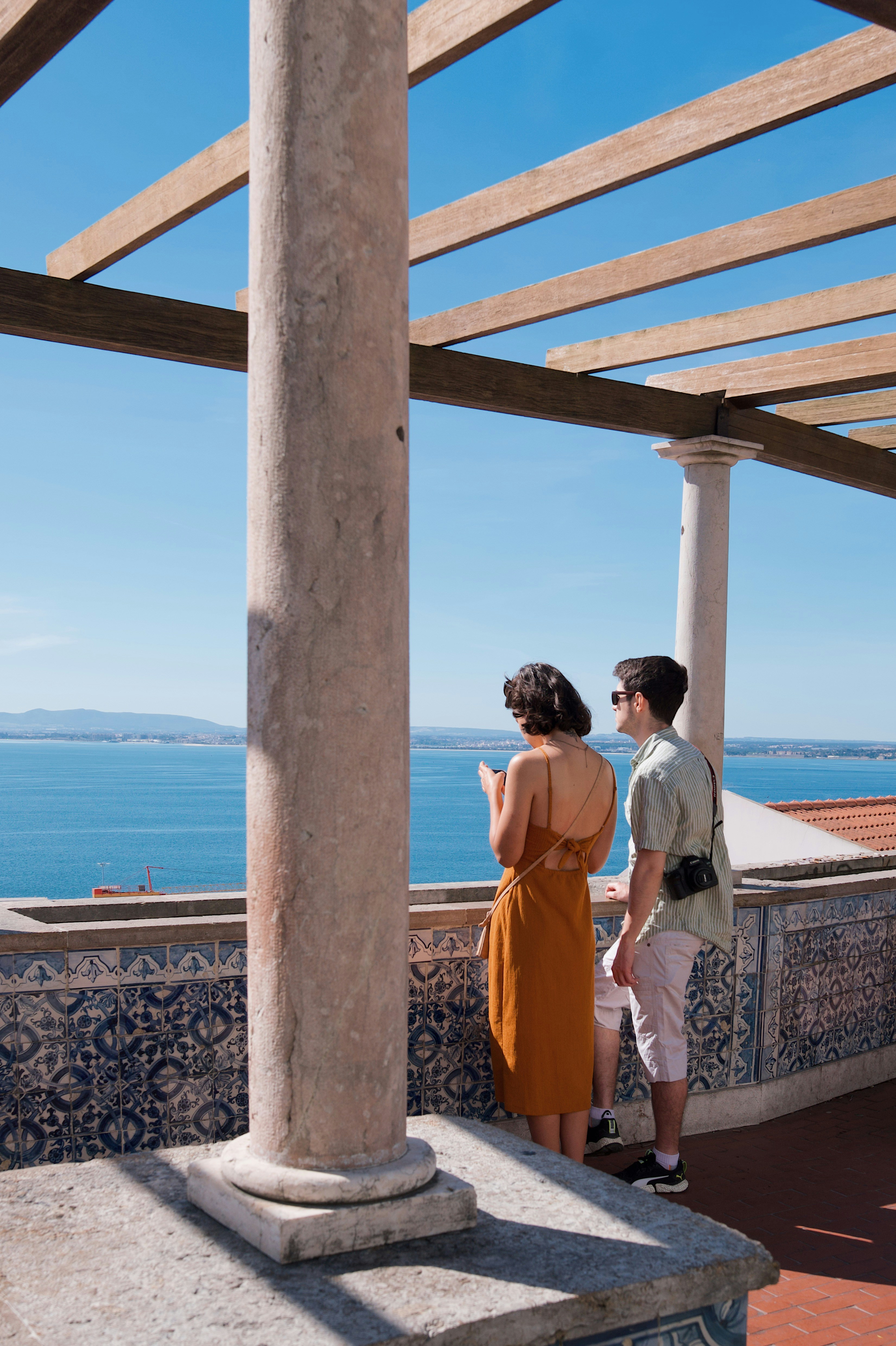 a man and a woman standing under a wooden structure
