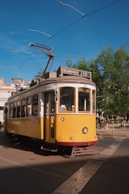 Close-up of a Fancy Heart Transportes car parked near a historic Lisbon building under a bright sky.
