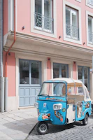 Tuk tuk parked at a colorful Alfama street with traditional tiles and sunlight