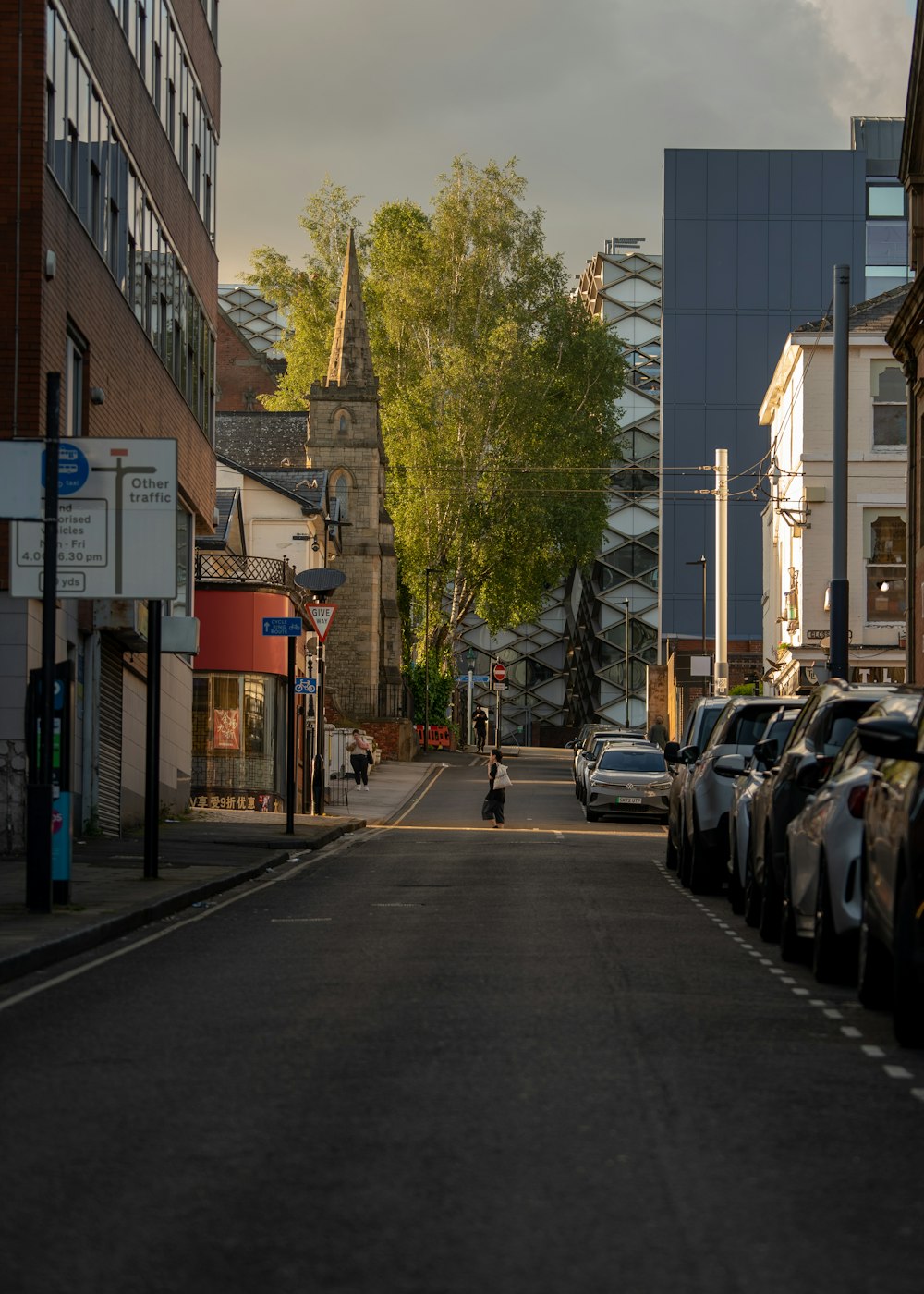 a person walking down a street next to parked cars