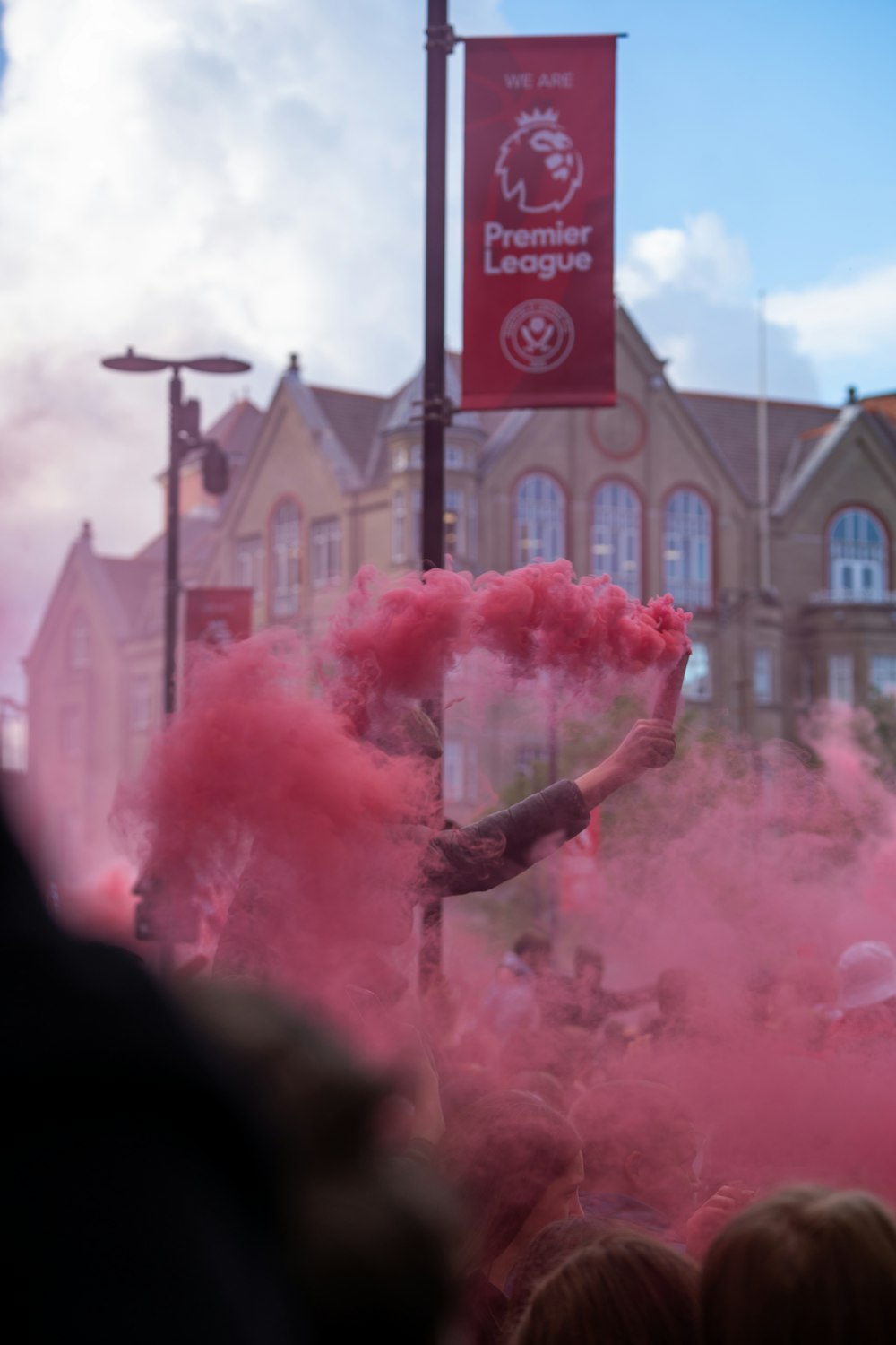 a group of people with pink smoke in front of a building