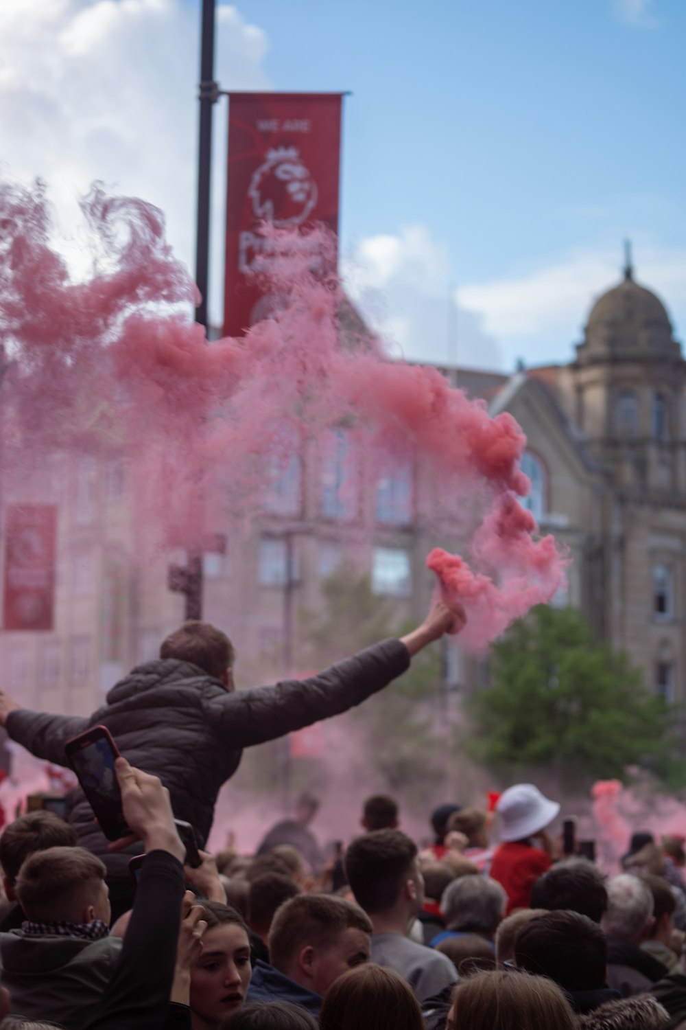 a crowd of people with pink smoke bombs in the air