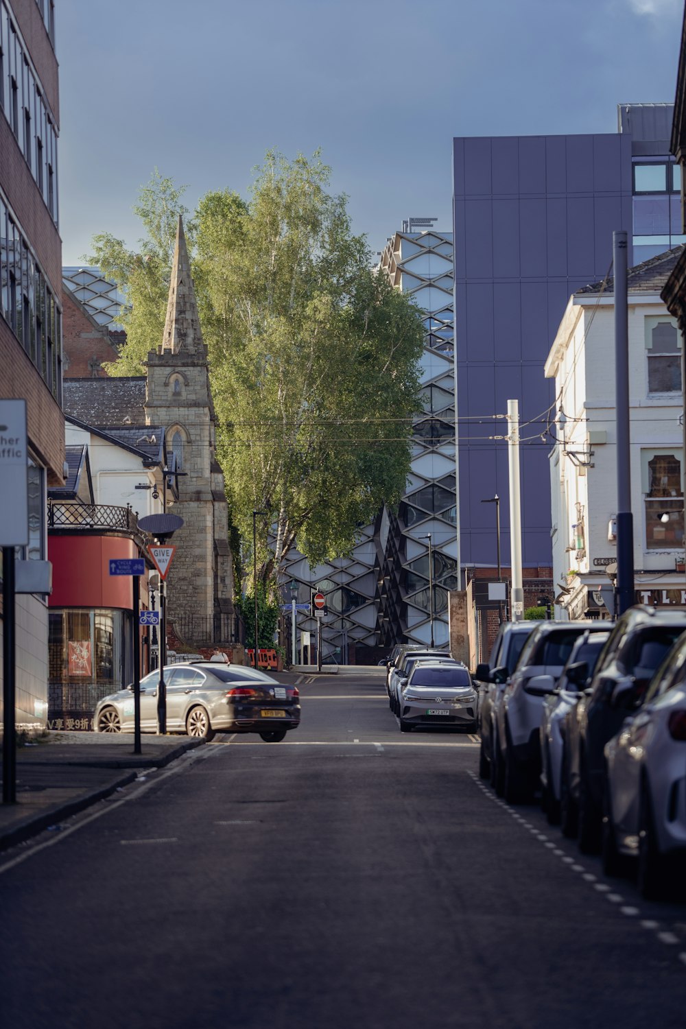 a city street lined with parked cars next to tall buildings