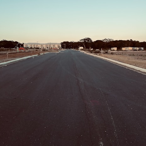 Empty paved road leading through a newly approved housing plot area.