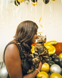 A smiling pet parent holding a basket of top-rated pet treats and toys, sharing a moment with their cat