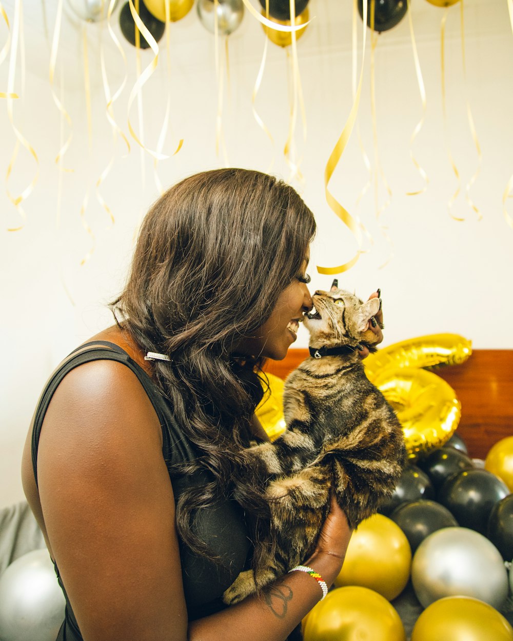 a woman holding a cat in front of balloons