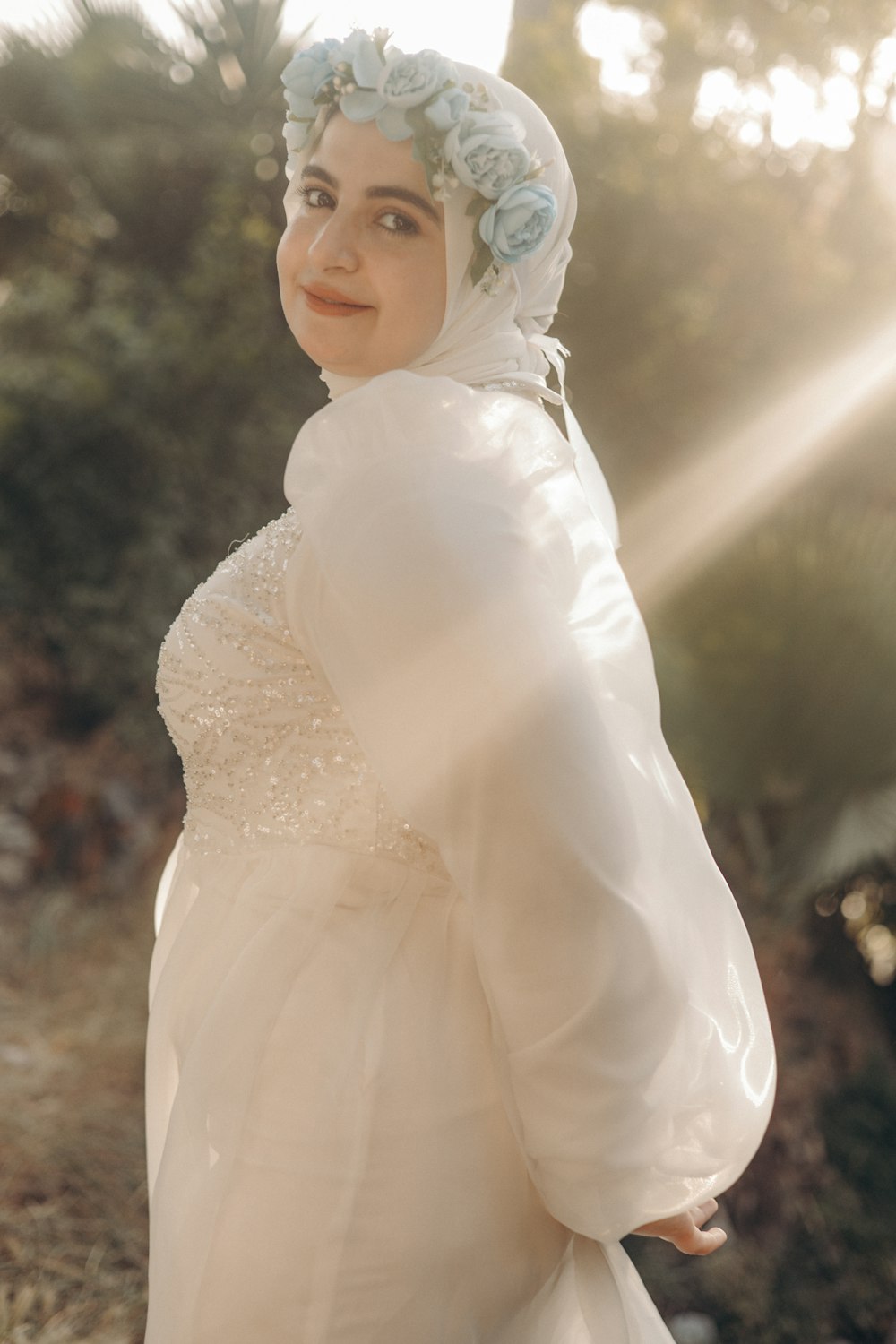 a woman wearing a white dress and a blue flower in her hair