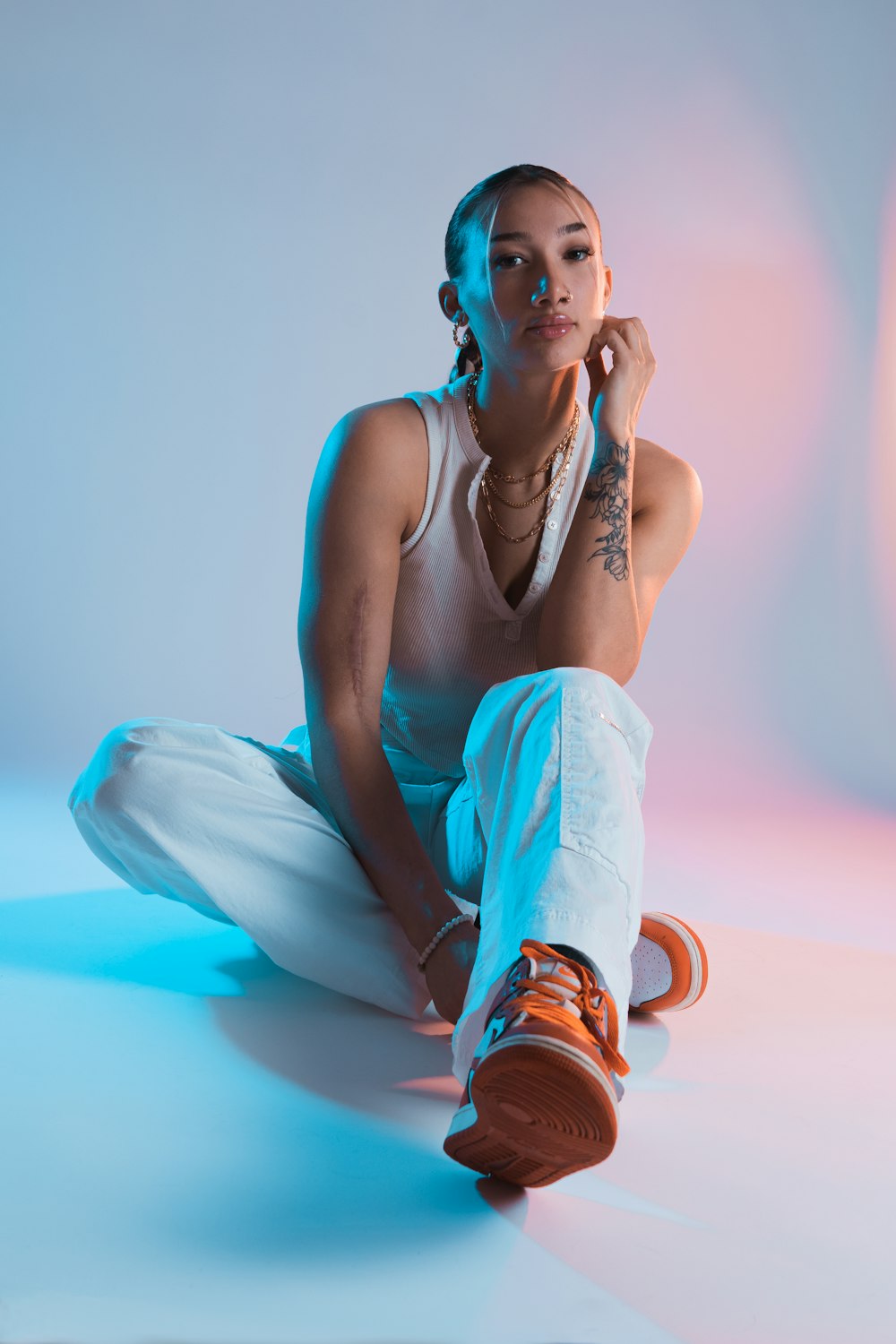 a woman sitting on the ground with a cell phone to her ear