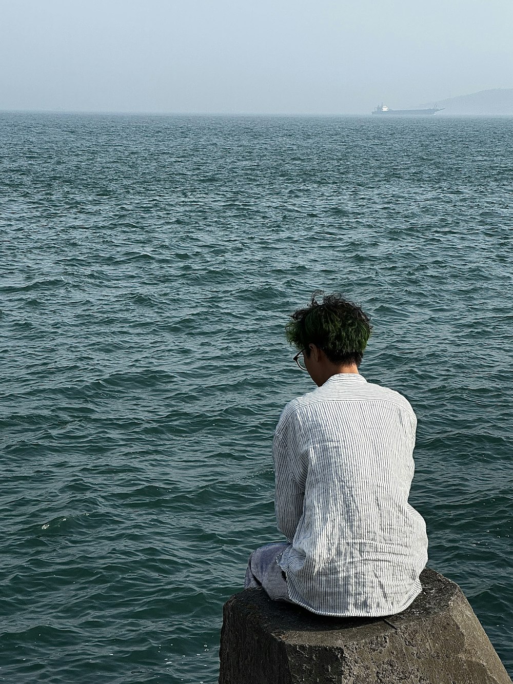 a person sitting on a rock looking out at the ocean