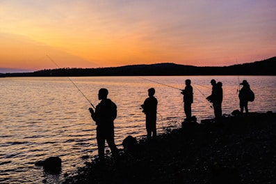 Family fishing together on the shore of West Fox Lake at sunset.