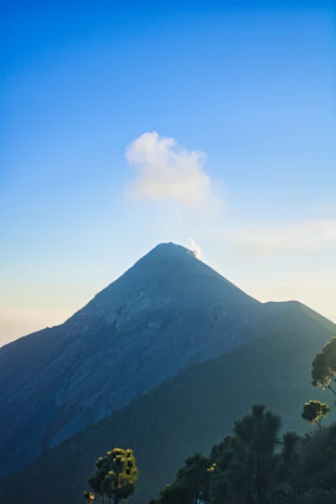 A panoramic view of a majestic volcano with smoke gently rising against a vibrant sky.
