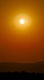 Close-up of a glowing sun with warm golden rays stretching across a clear sky.