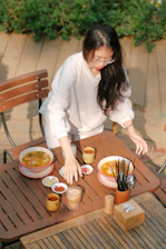A rustic wooden table set with steaming bowls of thukpa, colorful momos, and a pot of herbal tea, sunlight filtering through leaves.