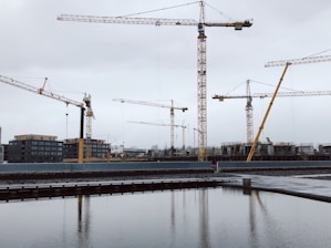 Construction team reviewing blueprints on a building site with cranes in the background.