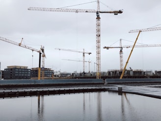 Engineers reviewing detailed structural drawings on a construction site with cranes in the background.