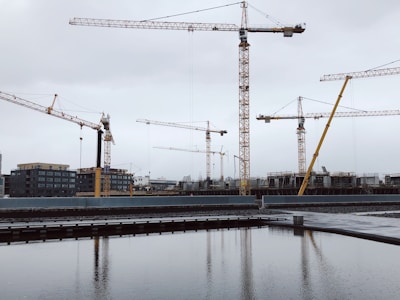 Construction team reviewing blueprints on a building site with cranes in the background.