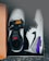 A pair of stylish white and black athletic shoes with orange and red branding, featuring purple and elephant print accents, placed inside a cardboard shoe box on a dark surface.