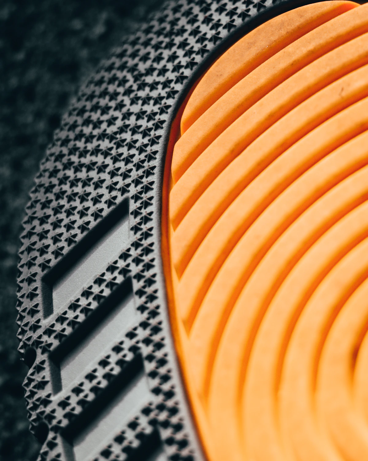 Trail running shoe sole, close macro on the knurled rubber tread and ridged midsole.