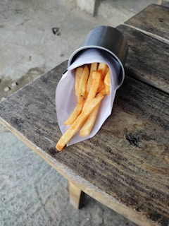 Crispy golden fries spilling out of a branded Meal For You paper cone on a rustic wooden table
