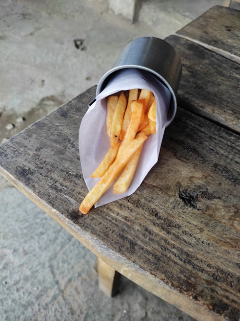 Crispy golden fries spilling out of a branded Meal For You paper cone on a rustic wooden table
