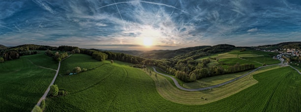 A panoramic view of two lush green hills under a sunrise gradient.