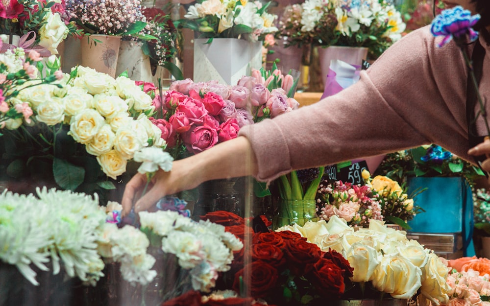 a woman reaching for a bouquet of flowers